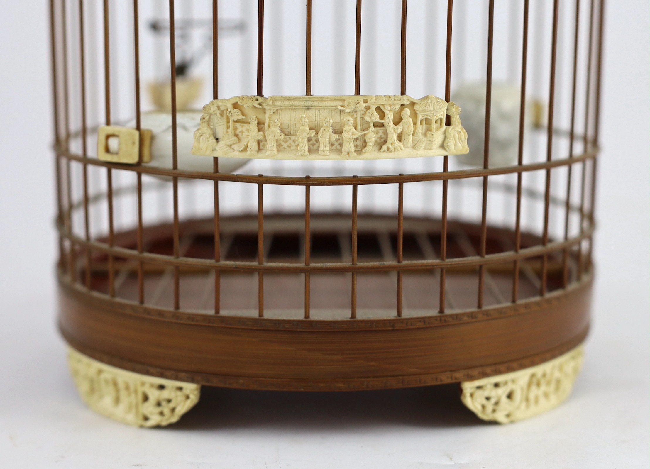A Chinese bamboo and Guangzhou ivory mounted bird cage, late Qing dynasty, with two Guangxu mark and period porcelain bird feeders (1875-1908), cage 32.5cm high to top of handle